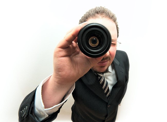 A suited man looking through a spyglass.