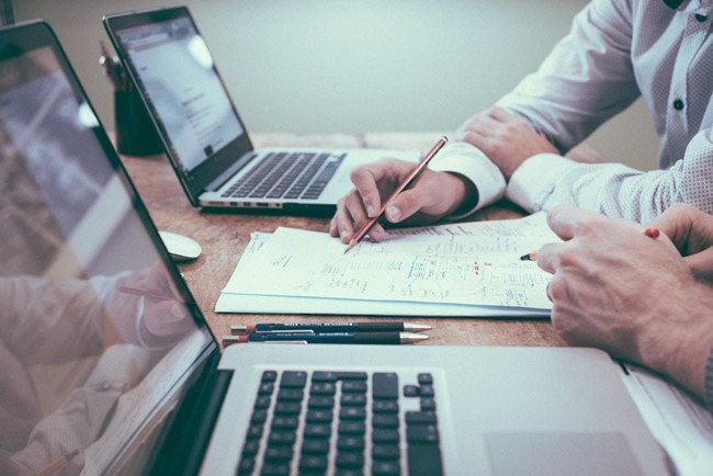  Two people planning an invoice on paper.